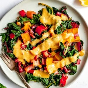 A plate of cooked rainbow chard, drizzled with vegan honey mustard.