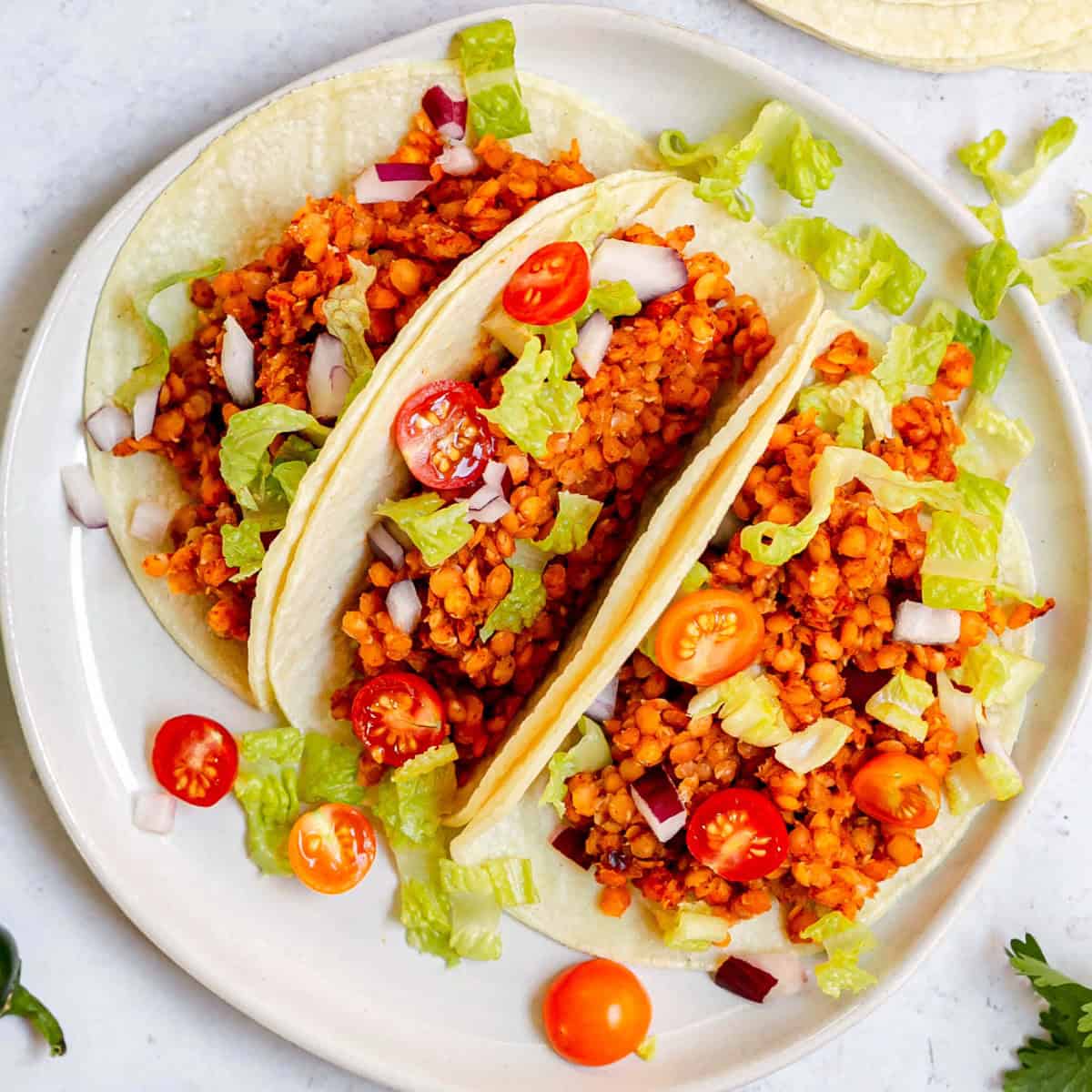 A plate of three red lentil tacos.