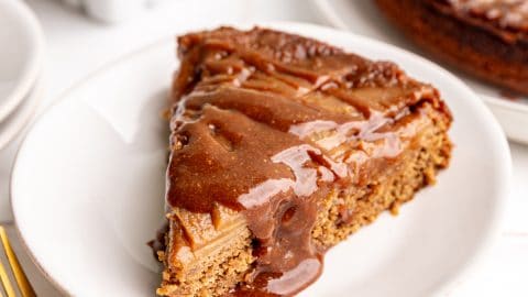 A slice of Vegan Apple Upside Down Cake, with a drizzle of caramel on top.