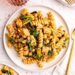 A plate of vegan creamy spinach pasta, with a fork and napkin, ready to eat.
