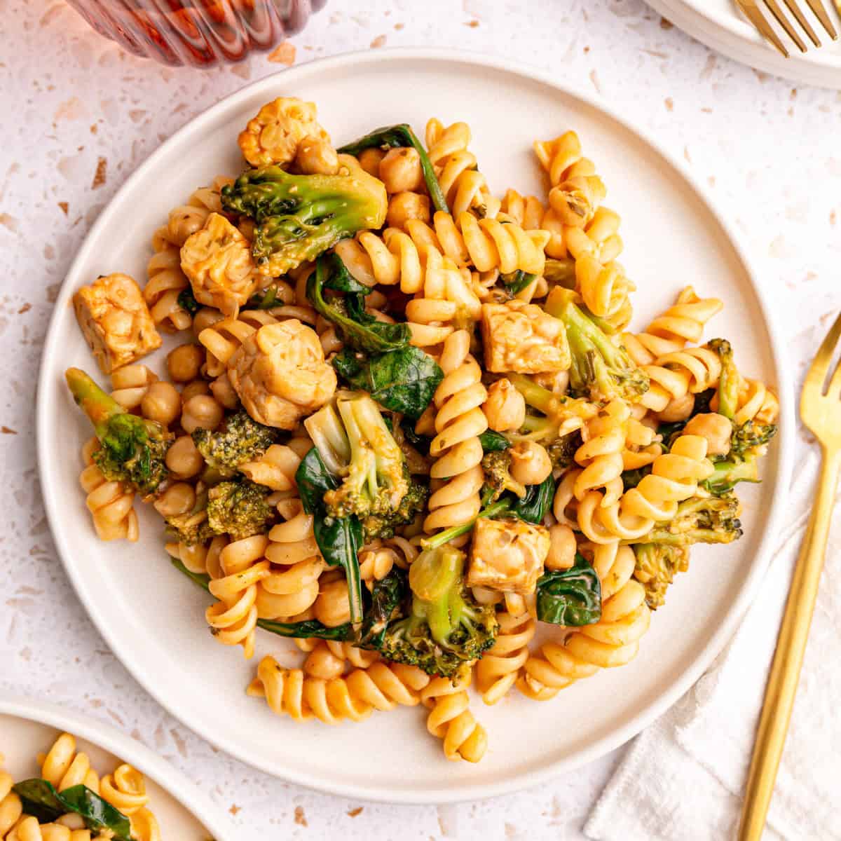 A plate of vegan creamy spinach pasta, with a fork and napkin, ready to eat.