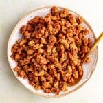 A bowl of vegan ground beef crumbles, with a spoon scooping some out.