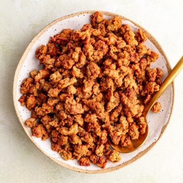 A bowl of vegan ground beef crumbles, with a spoon scooping some out.