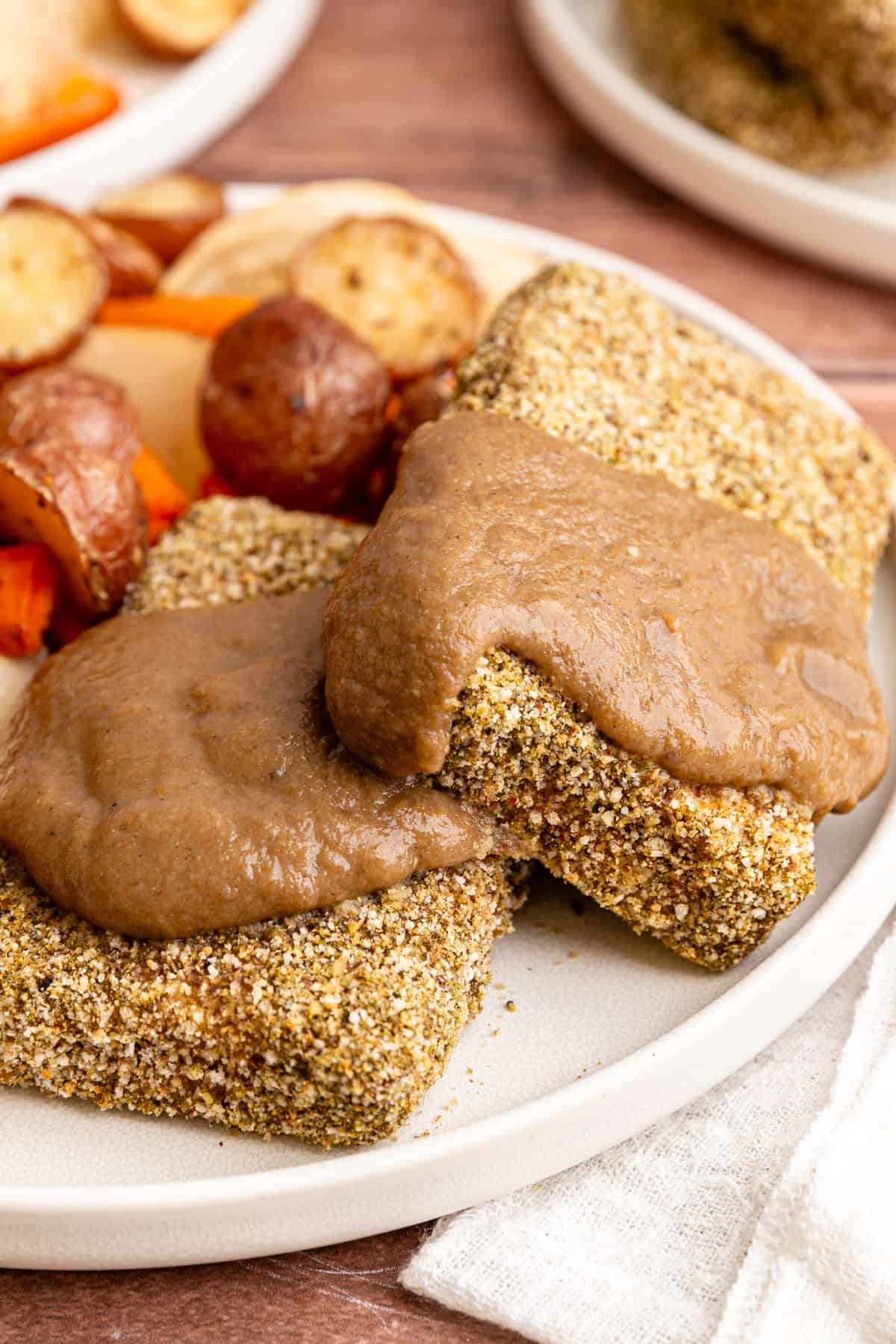 Two slices of Thanksgiving Tofu on a plate, covered with mushroom gravy.