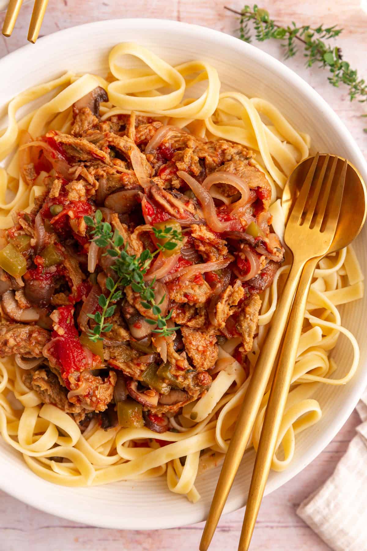 A bowl of vegan cacciatore with a fork and spoon, ready to eat.