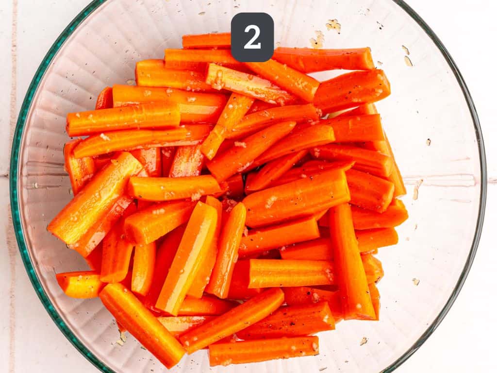Vegan Glazed Carrots Step - toss the carrots with syrup, broth, garlic, salt, and pepper.