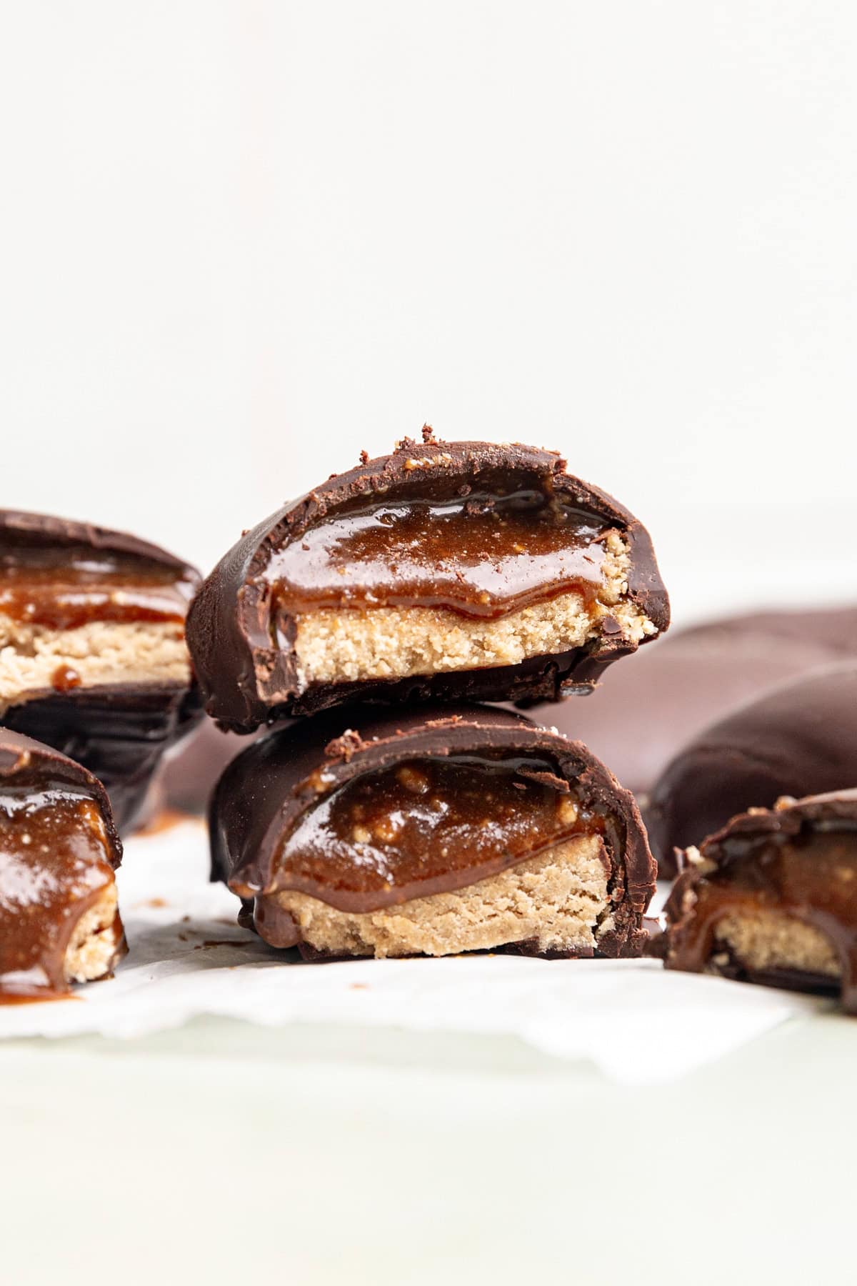 Many vegan milky way bars, cut in half to see the nougat and caramel layers.