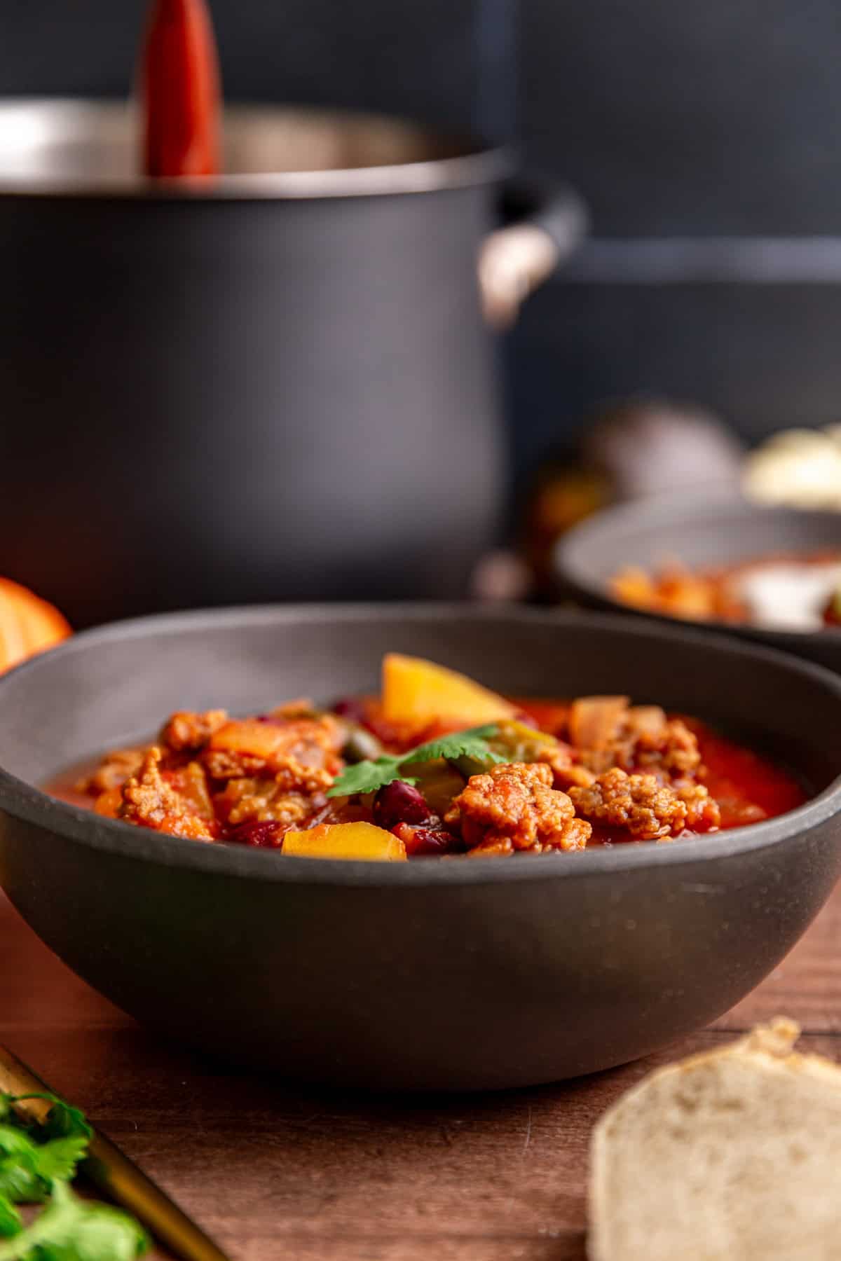 A bowl of vegan pumpkin chili next to the pot of chili.