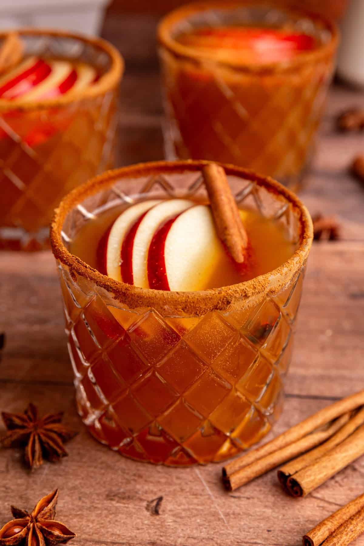 A glass of Thanksgiving mocktail, garnished with cinnamon sticks.