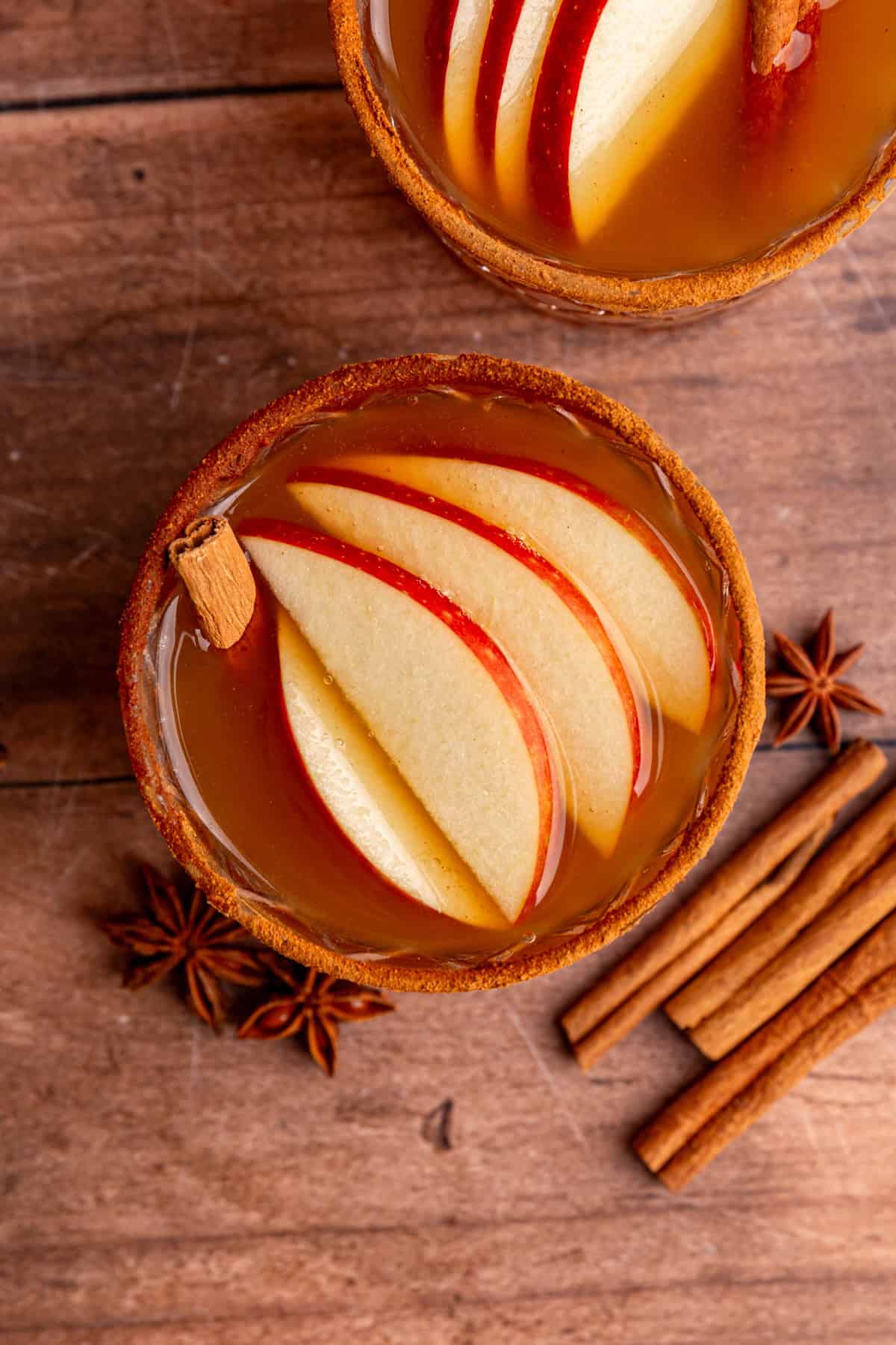 A glass of Thanksgiving mocktail, viewed from the top to see the apple slice garnish.