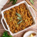 A dish of freshly baked vegan cornbread stuffing, garnished with sage.