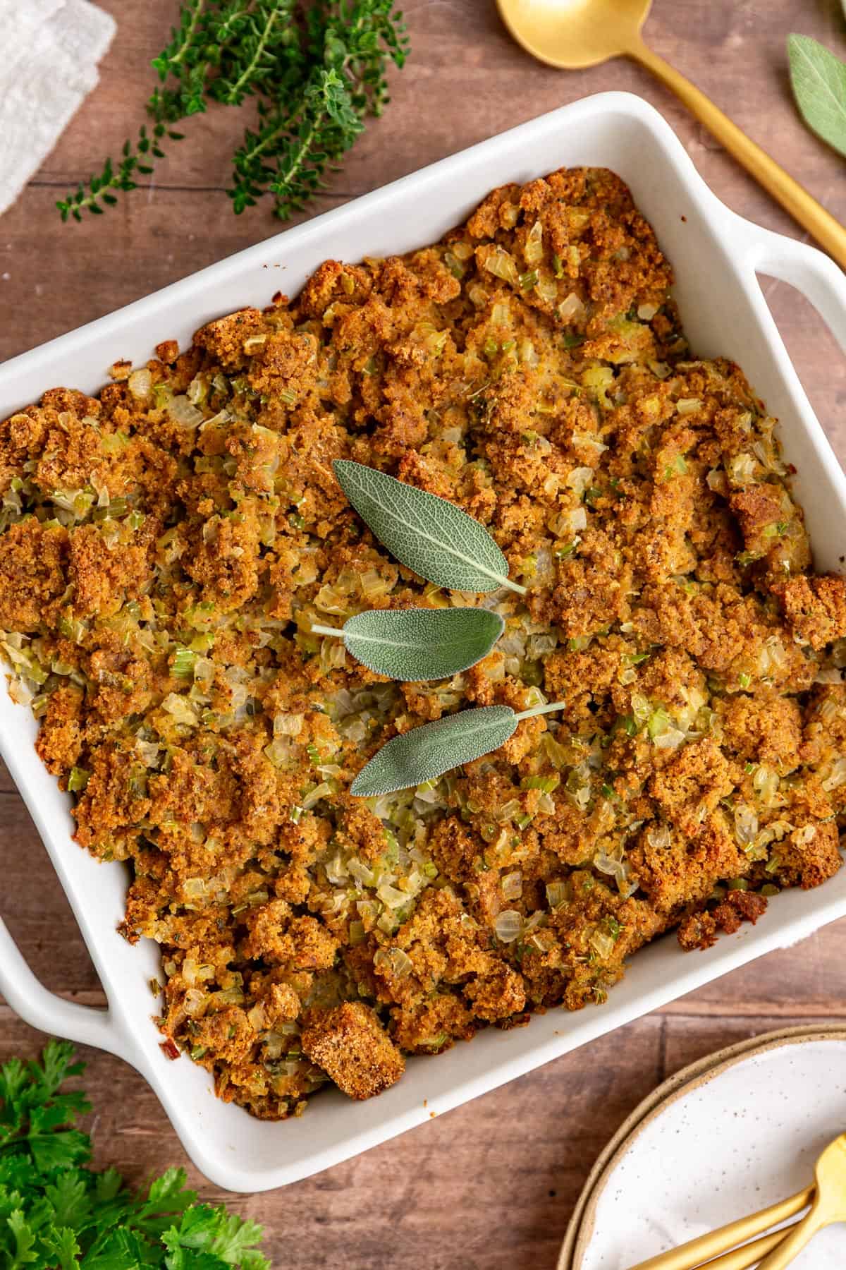 A dish of freshly baked vegan cornbread stuffing, garnished with sage.