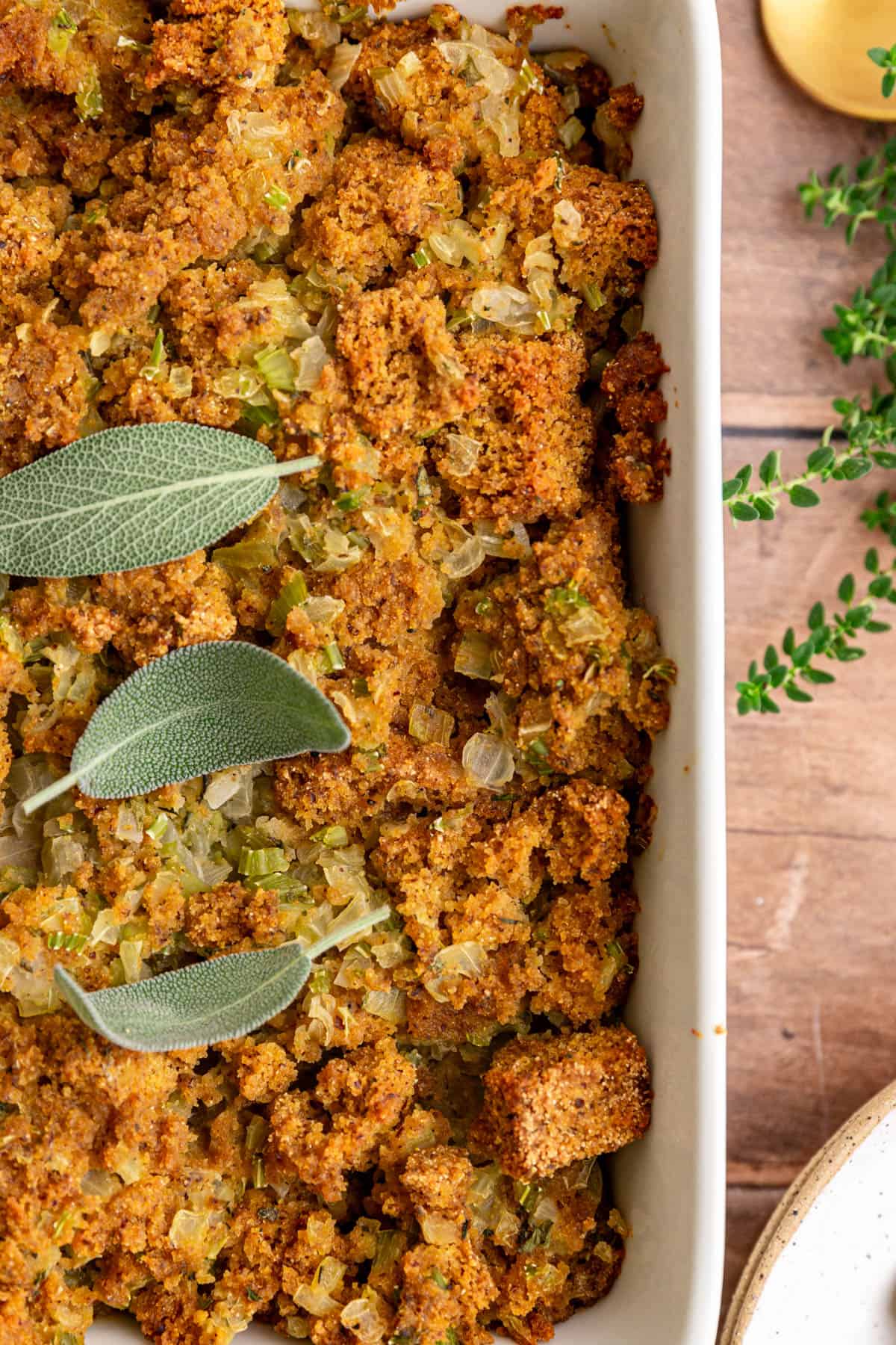 A dish of freshly baked vegan cornbread stuffing, garnished with sage.