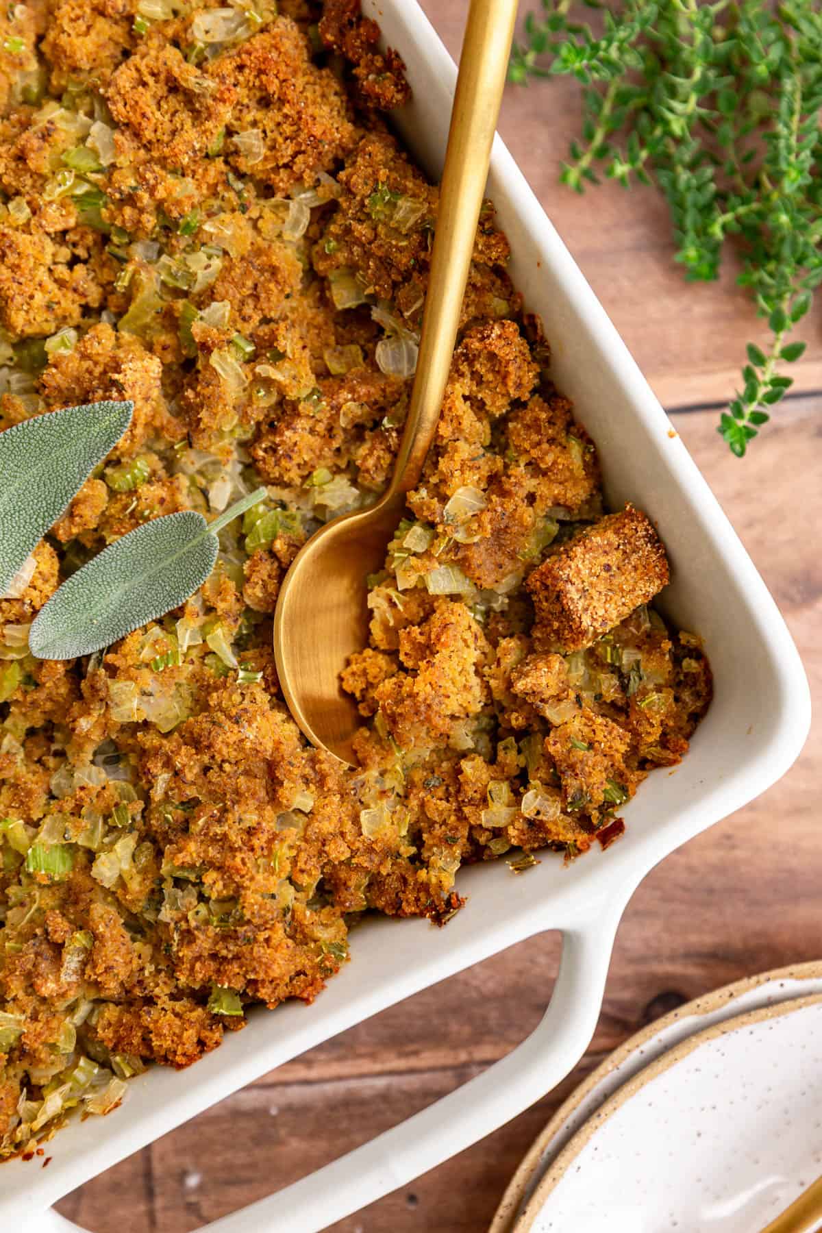 A dish of vegan cornbread stuffing, with a spoon scooping out a serving.