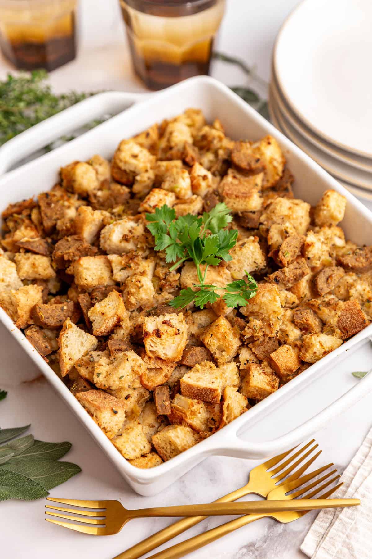 A baking dish filled with vegan sausage stuffing, garnished with parsley.