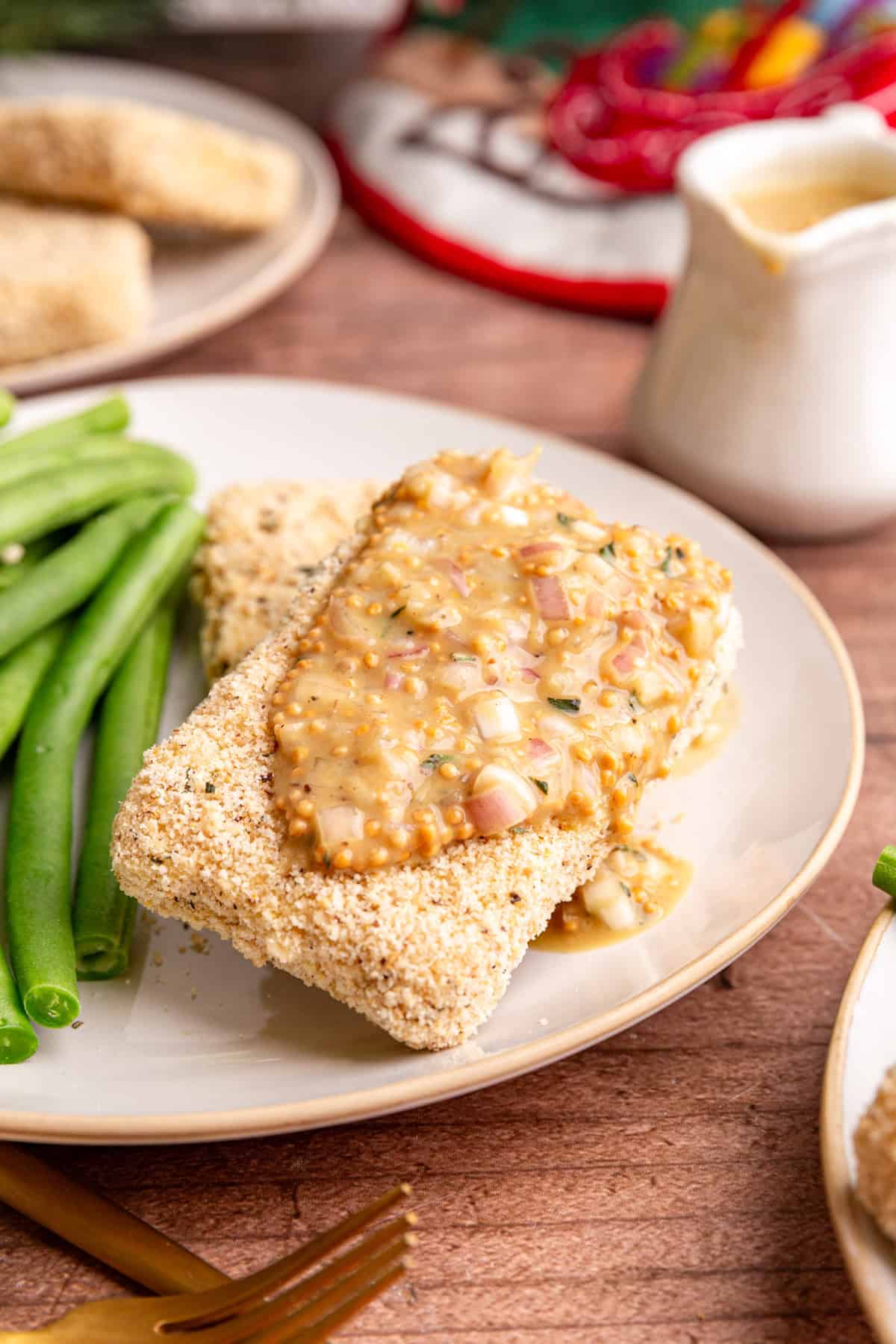 Two tofu cutlets on a plate, with a generous drizzle of mustard vinaigrette, and green beans on the side.