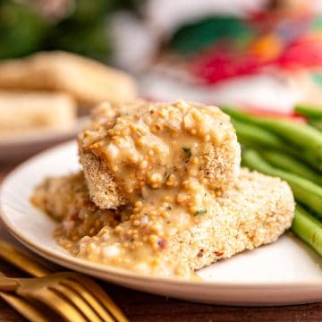 Two Christmas tofu cutlets on a plate, with a generous drizzle of mustard vinaigrette..