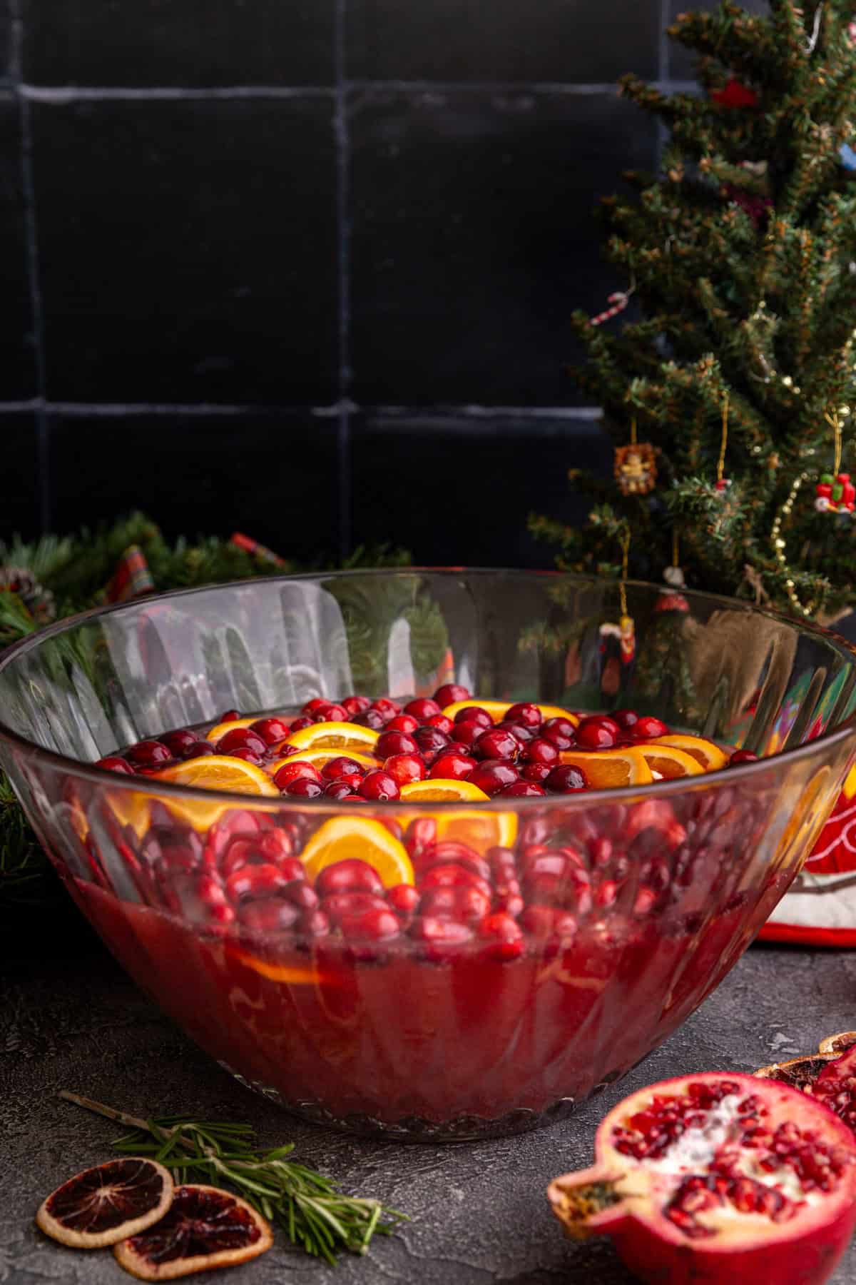 A punch bowl on a counter, with a Christmas tree.