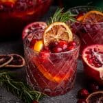 A glass of Non-Alcoholic Christmas Punch, garnished with rosemary and dried orange.
