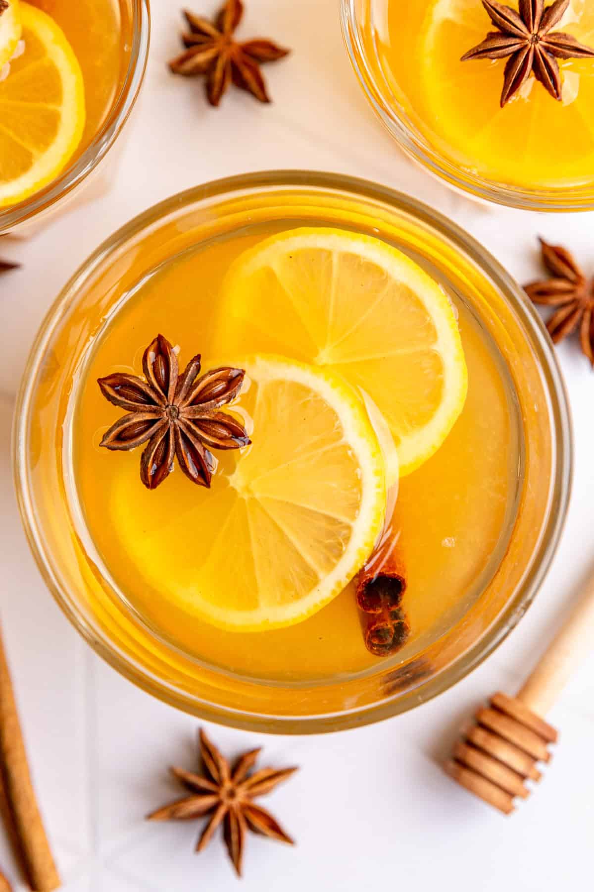 A top down view of a glass of hot toddy, with two lemon slices and a star anise.