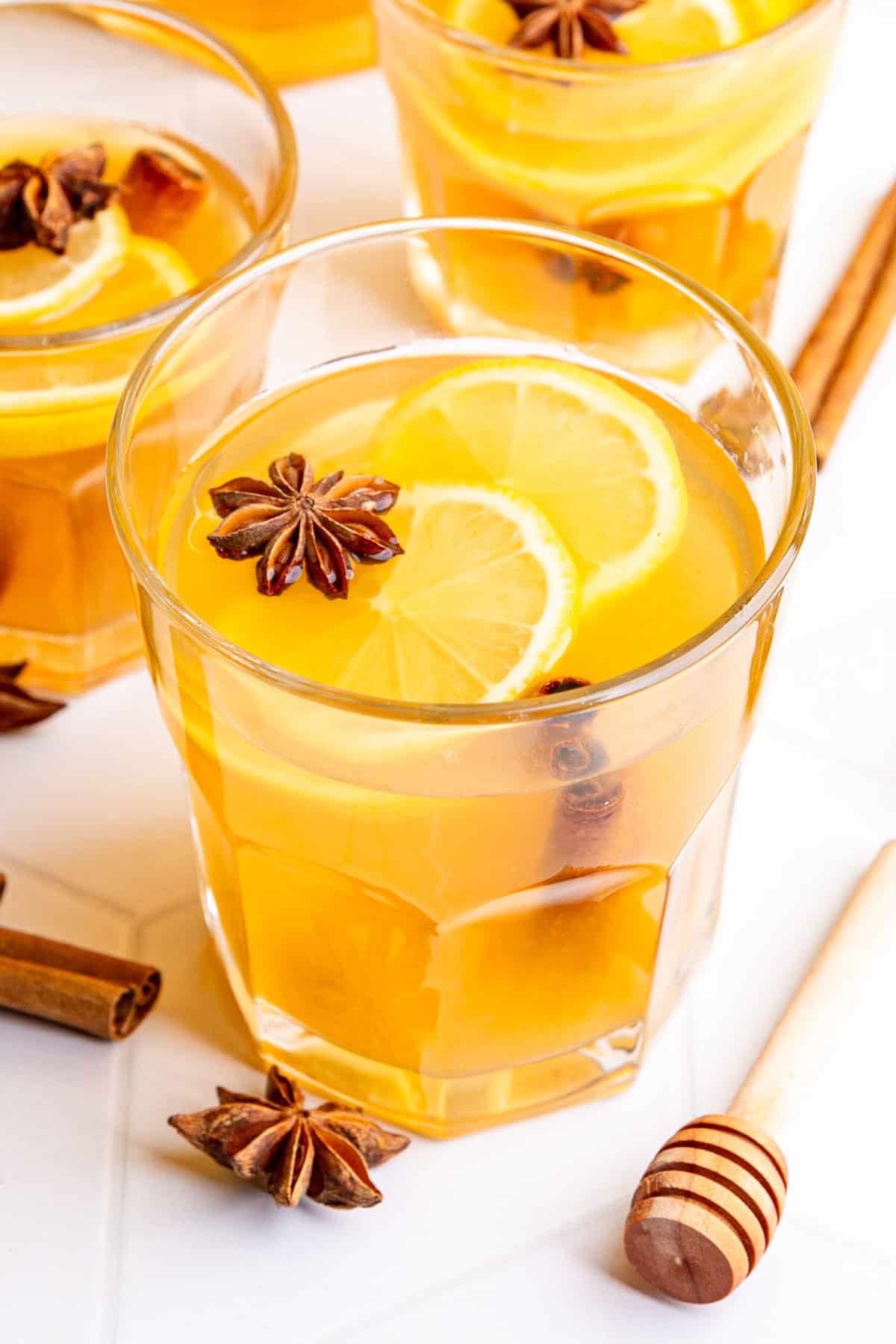 Several glasses hot toddies, garnished with lemon slices and star anise.