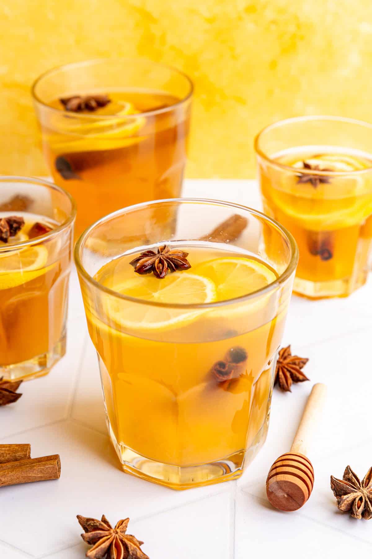 Several glasses of hot toddies, garnished with lemon slices and star anise.