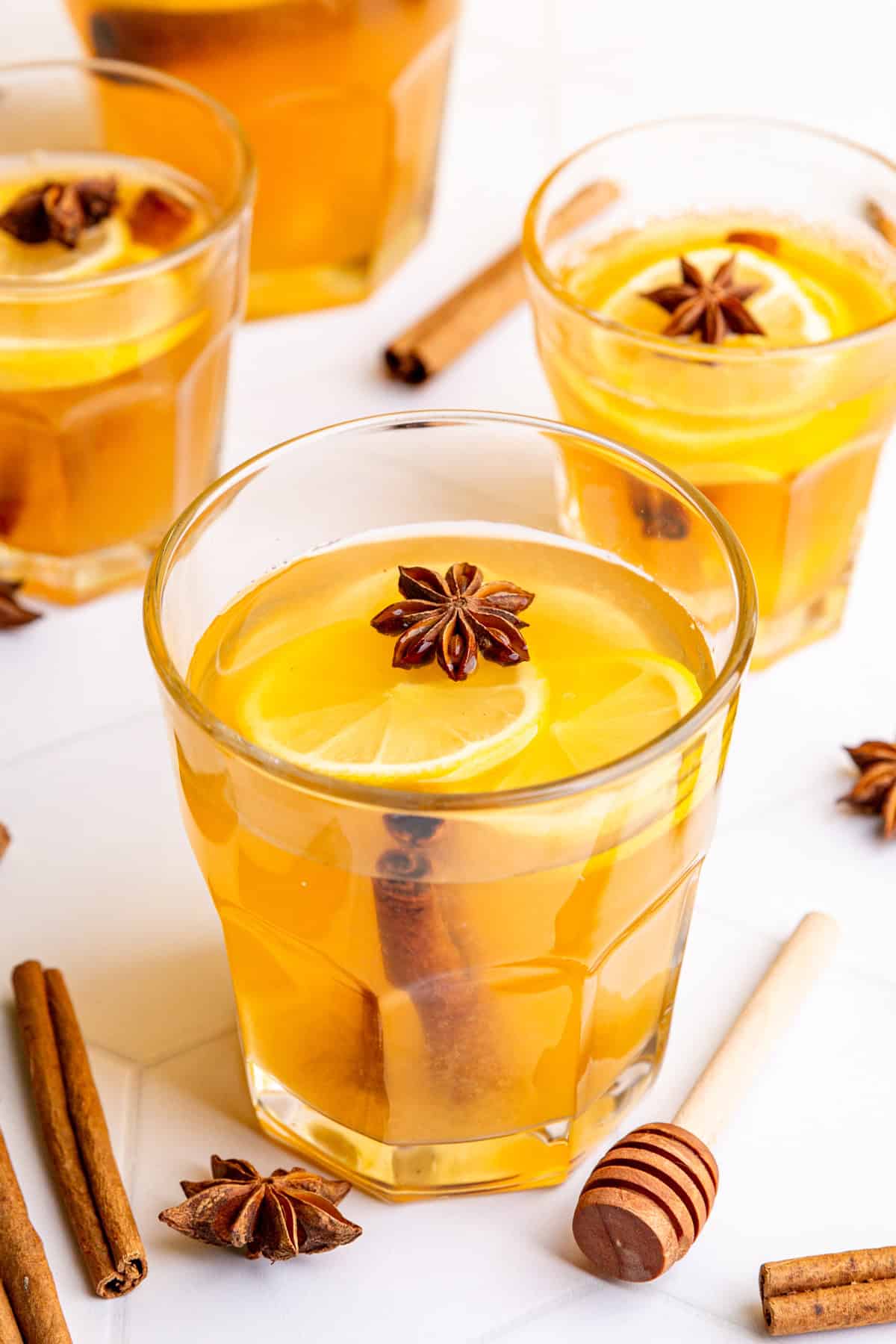 Several glasses of hot toddies, garnished with lemon slices and star anise.