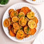 A plate of baked sweet potato rounds, garnished with parsley and salt.