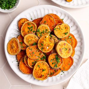 A plate of baked sweet potato rounds, garnished with parsley and salt.