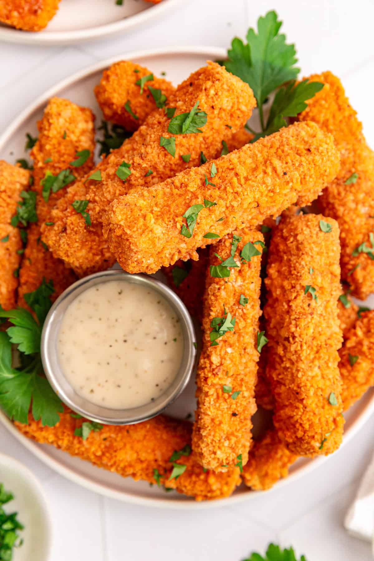 A plate of buffalo tofu wings garnished with parsley and served with vegan ranch.