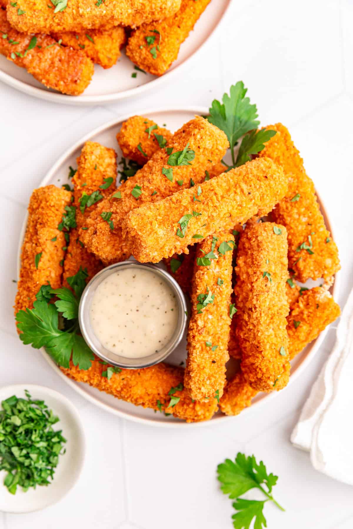 A plate of buffalo tofu wings garnished with parsley and served with vegan ranch.