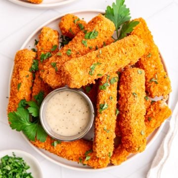 A plate of buffalo tofu wings garnished with parsley and served with vegan ranch.