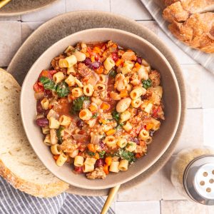 A bowl of Vegan Pasta e Fagioli, with a piece of bread.