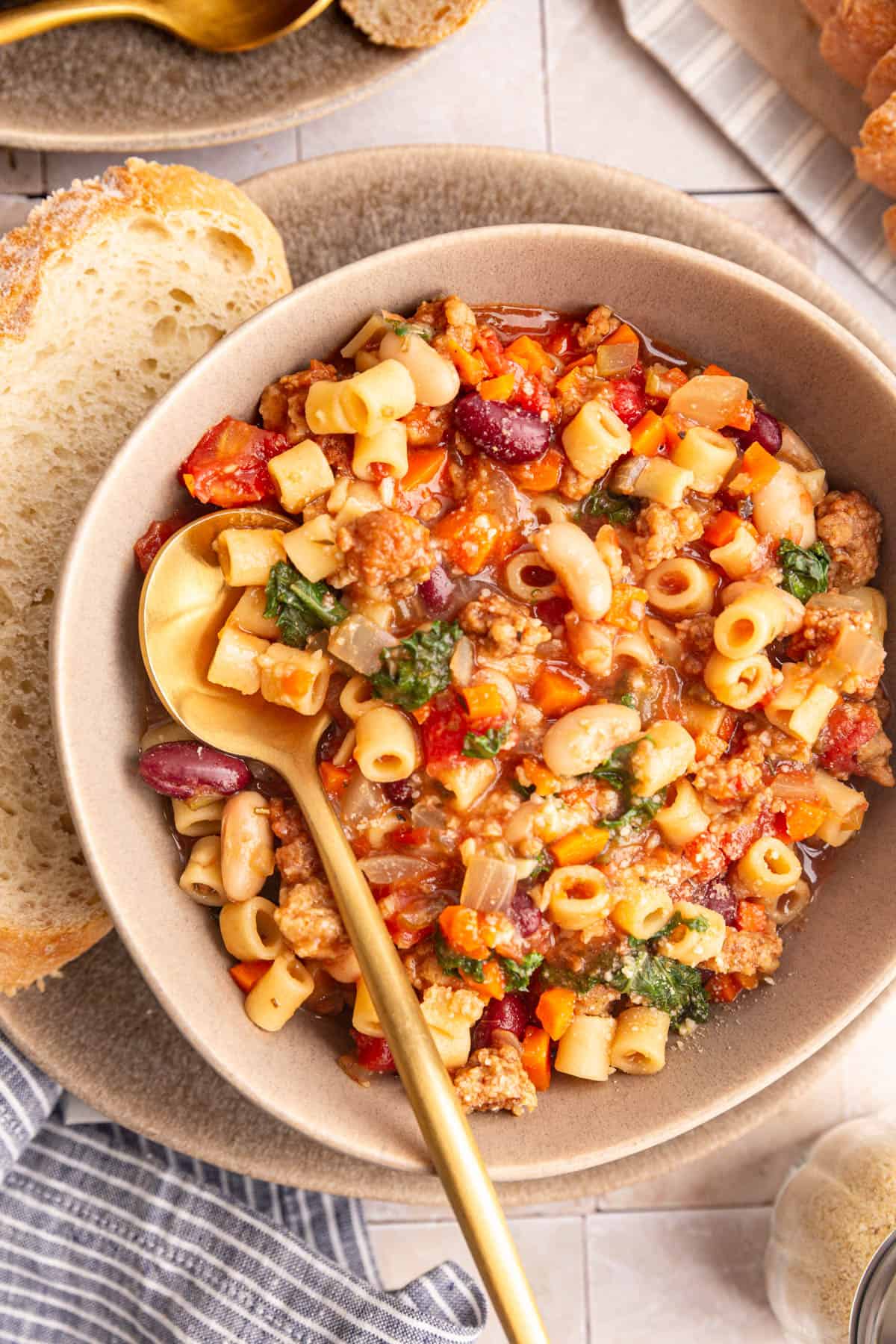 A bowl of Vegan Pasta e Fagioli, with a spoon, and a piece of bread.
