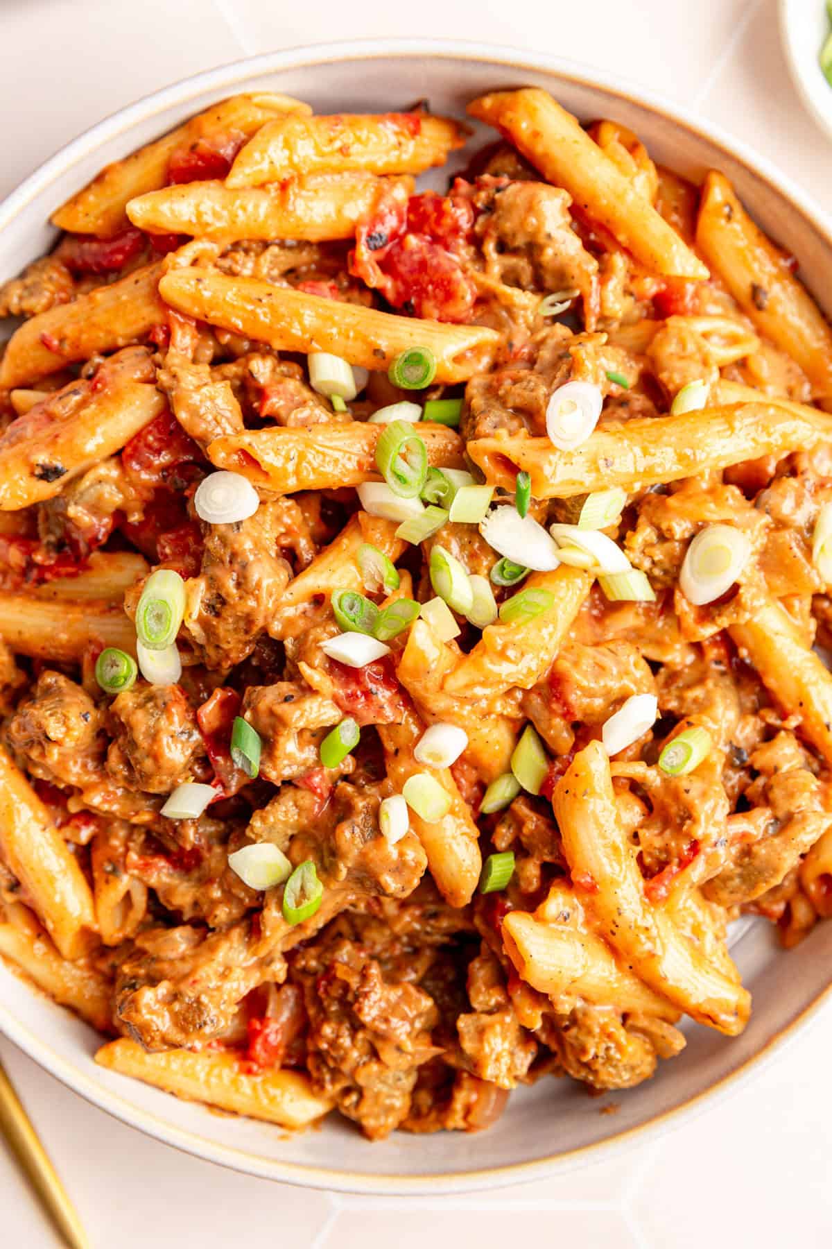 A bowl of vegan Cajun chicken pasta topped with scallions.