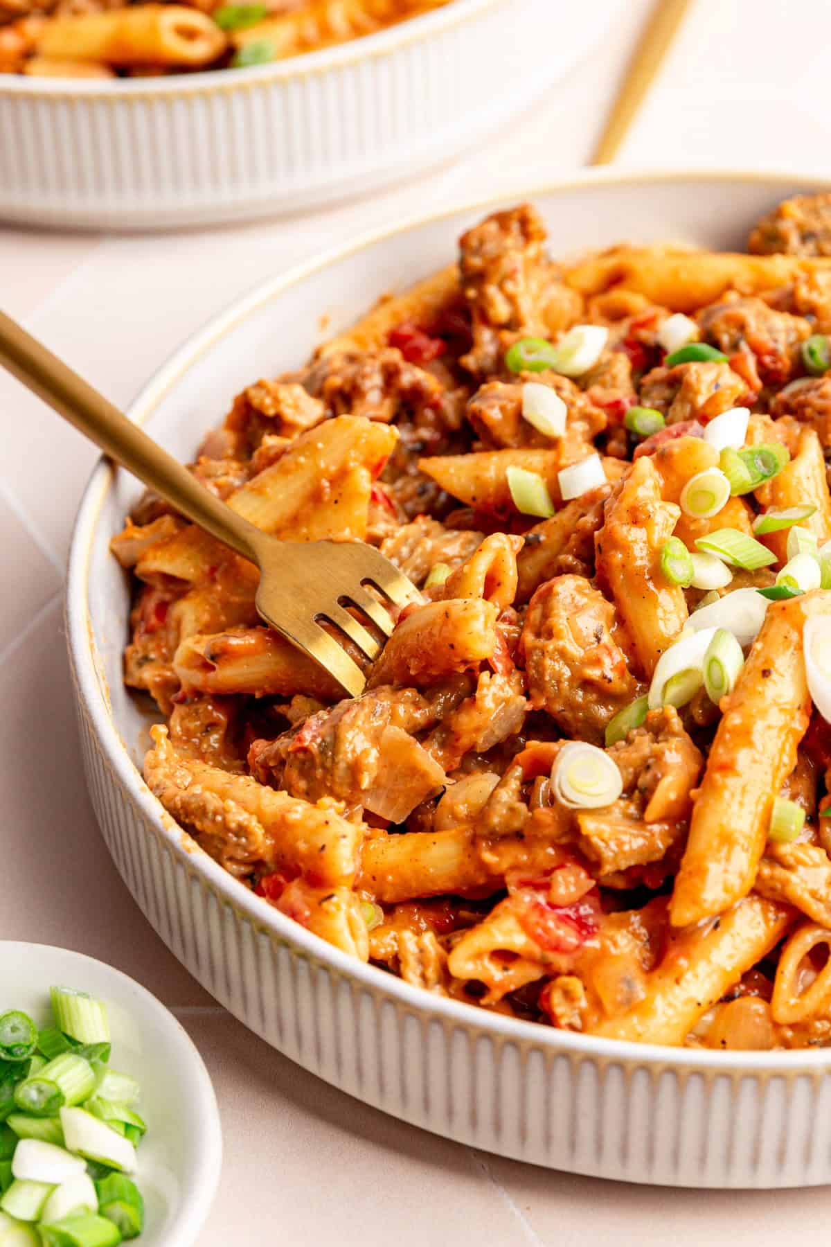 A bowl of vegan Cajun chicken pasta, with a fork taking out a bite.
