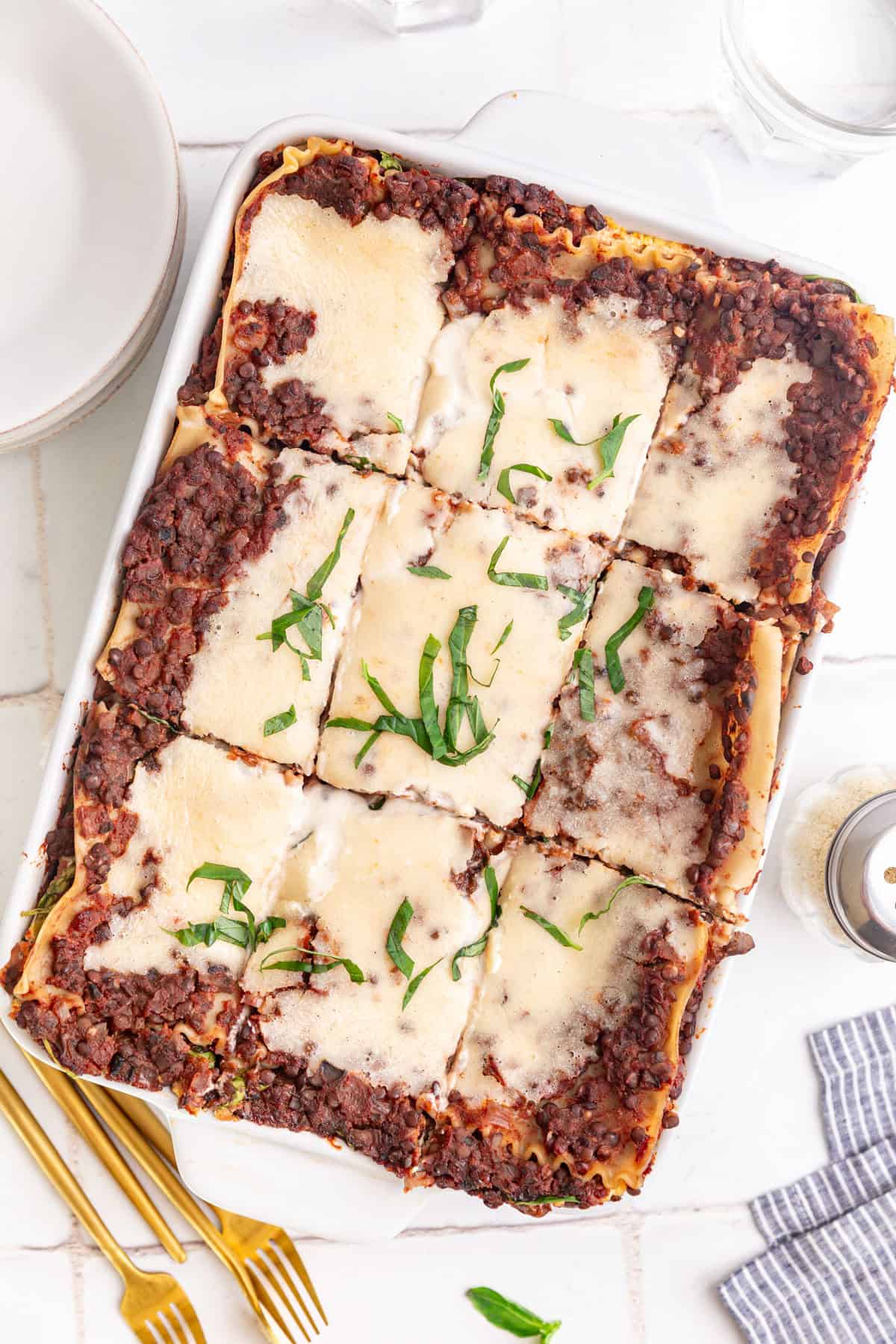 A casserole dish of lasagna, sliced, ready to serve.
