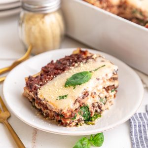 A slice of vegan lasagna topped with a basil leaf.