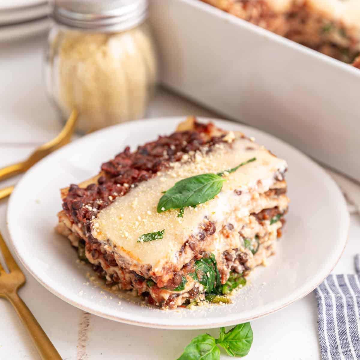 A slice of vegan lasagna topped with a basil leaf.