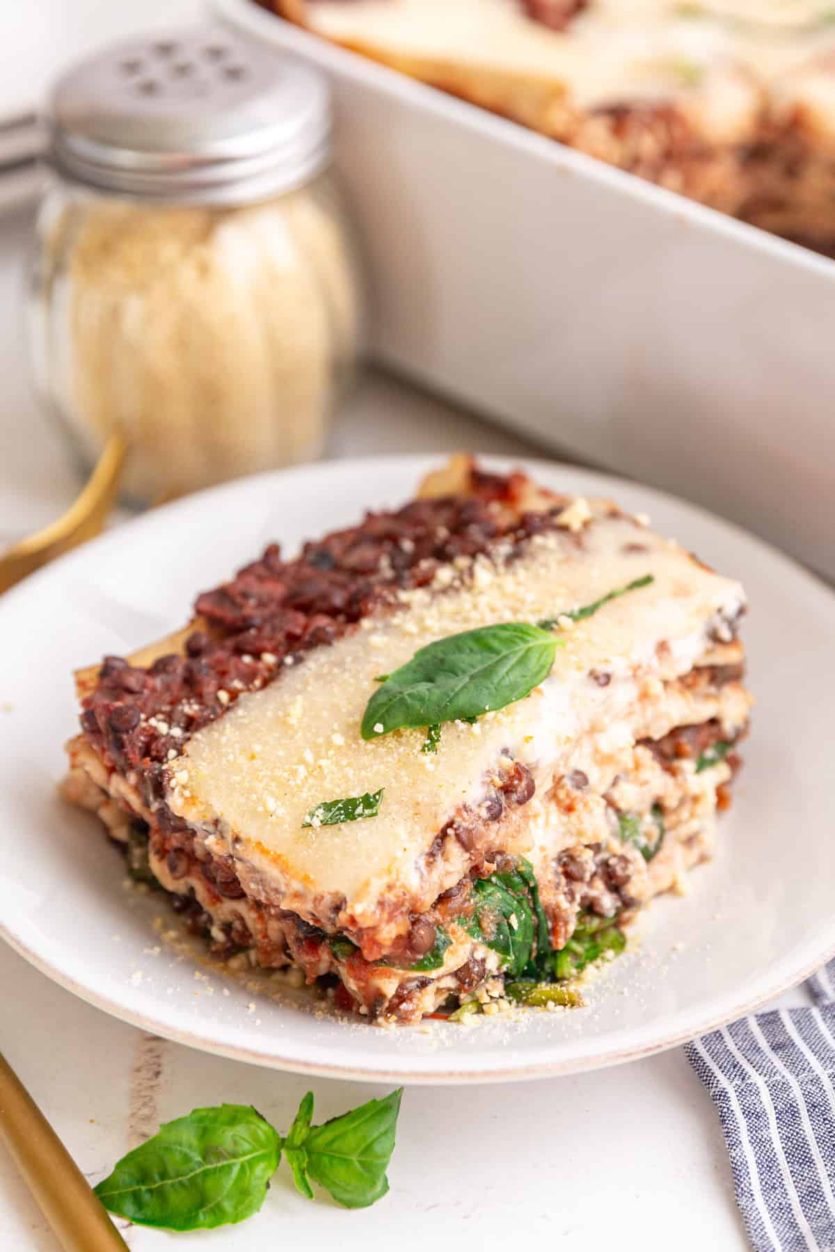 A slice of vegan lasagna topped with a basil leaf.