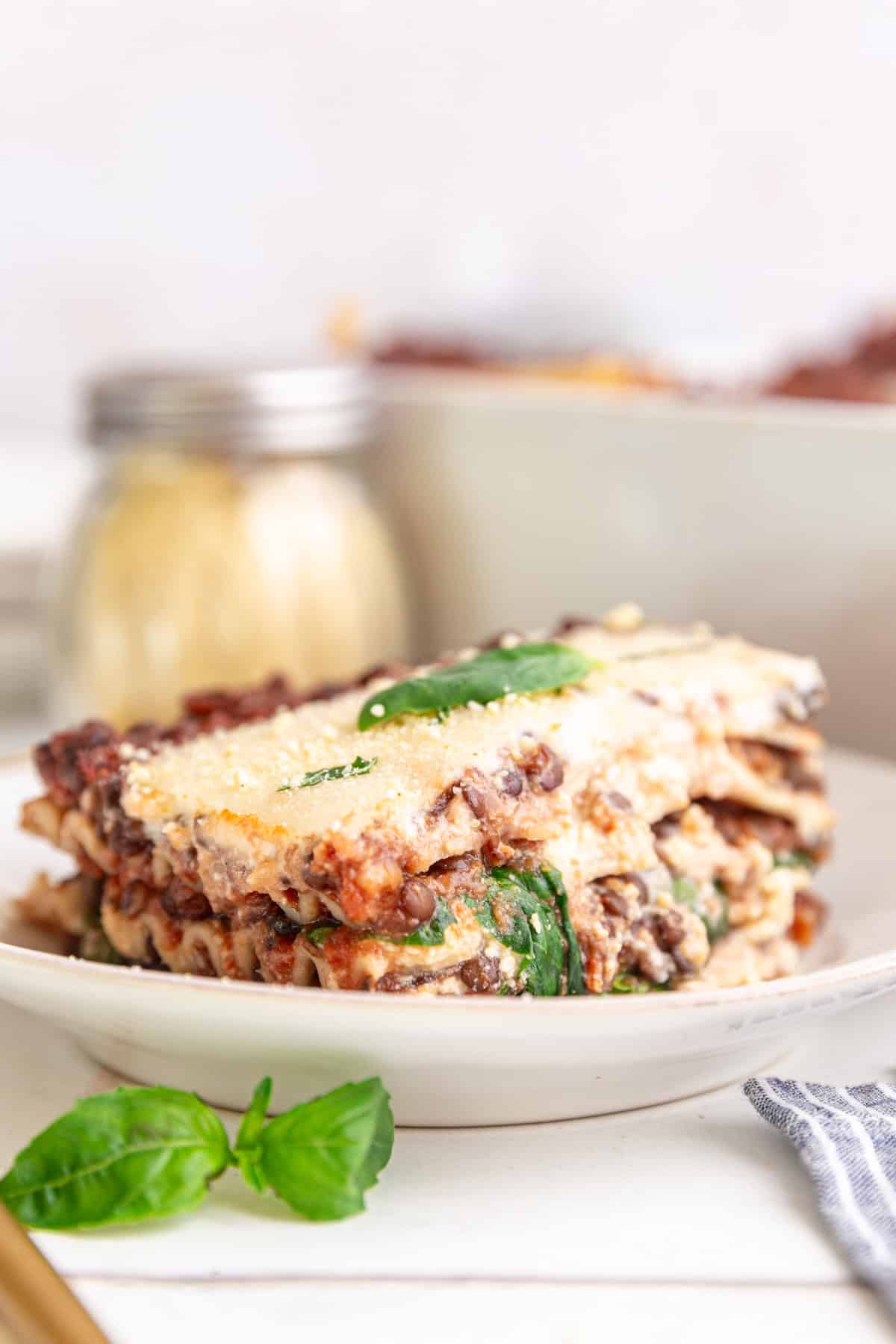 A slice of vegan lasagna, viewed from the side to see the layers.
