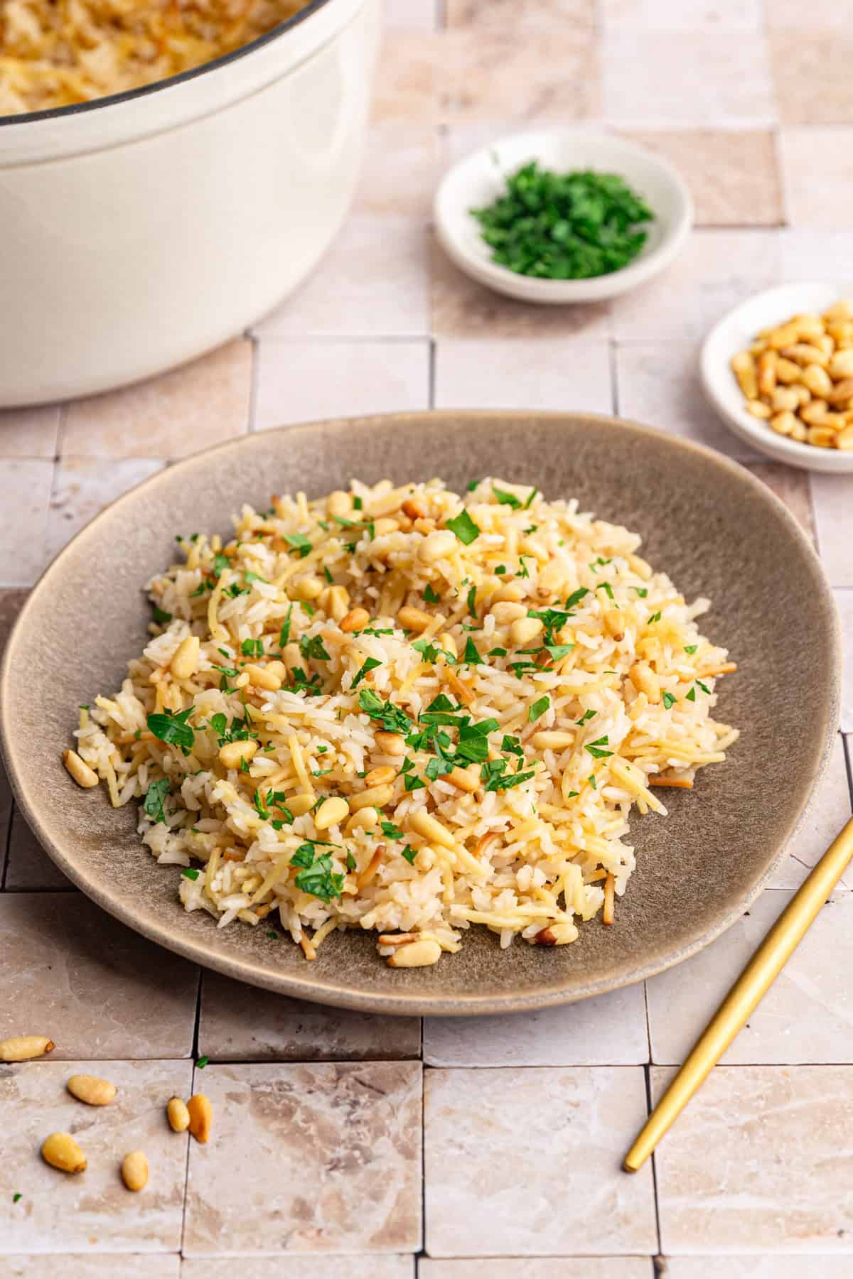A plate of vegan rice pilaf, garnished with pine nuts and fresh parsley.