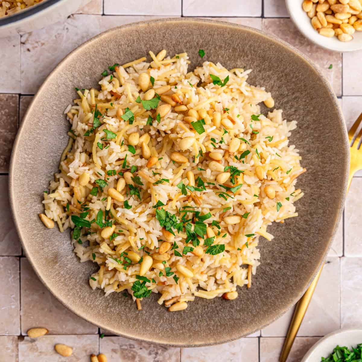 A plate of vegan rice pilaf, garnished with pine nuts and fresh parsley.