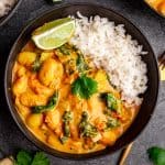 A bowl of rice and butter bean curry, with a lime wedge.