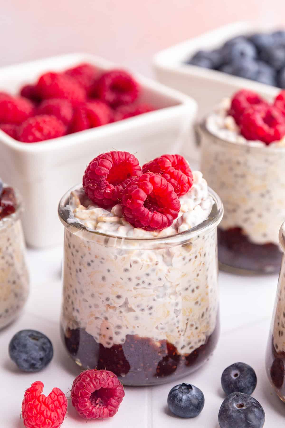 A jar of coconut milk overnight oats with jam on the bottom, topped with raspberries.