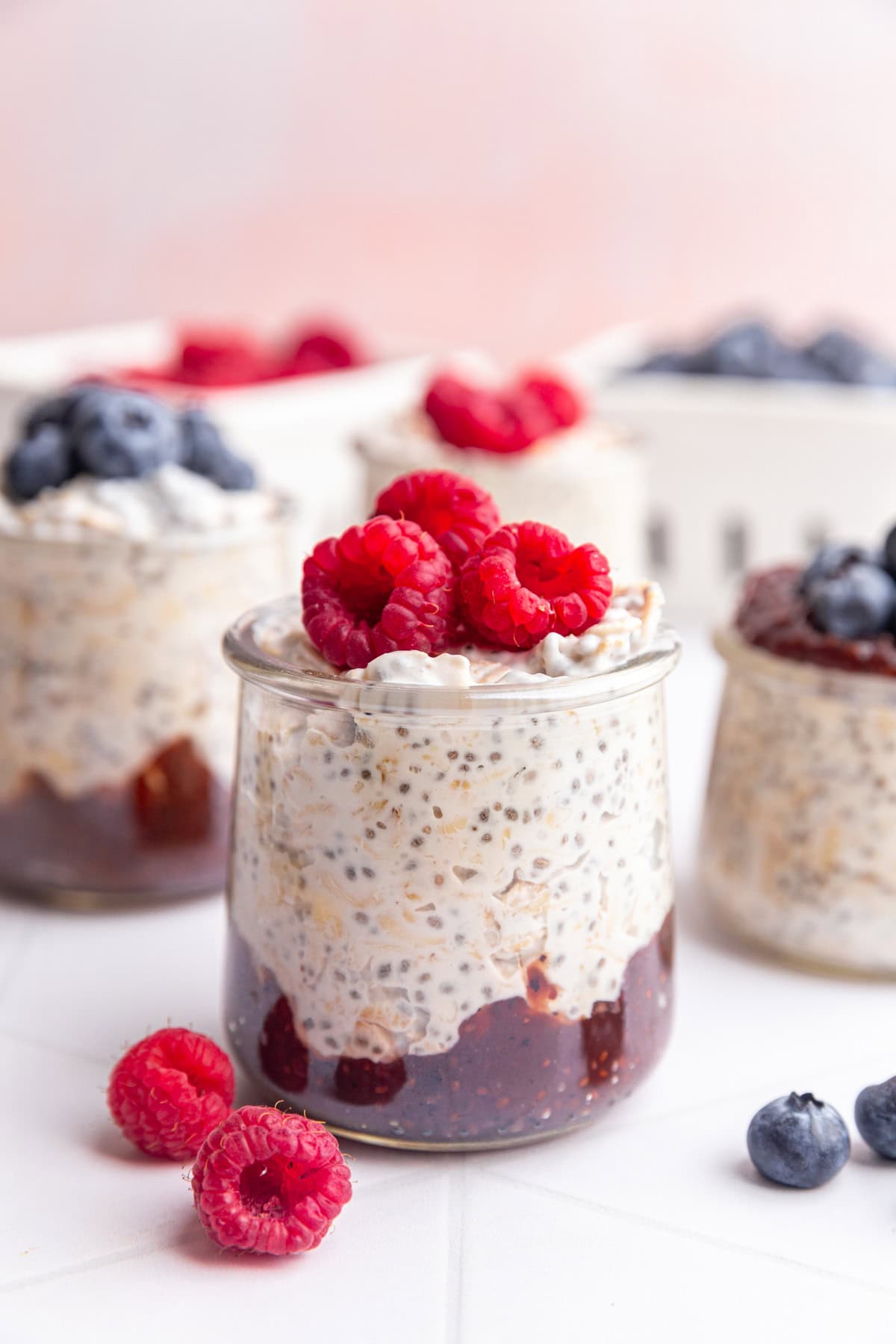 A jar of coconut milk overnight oats topped with raspberries.
