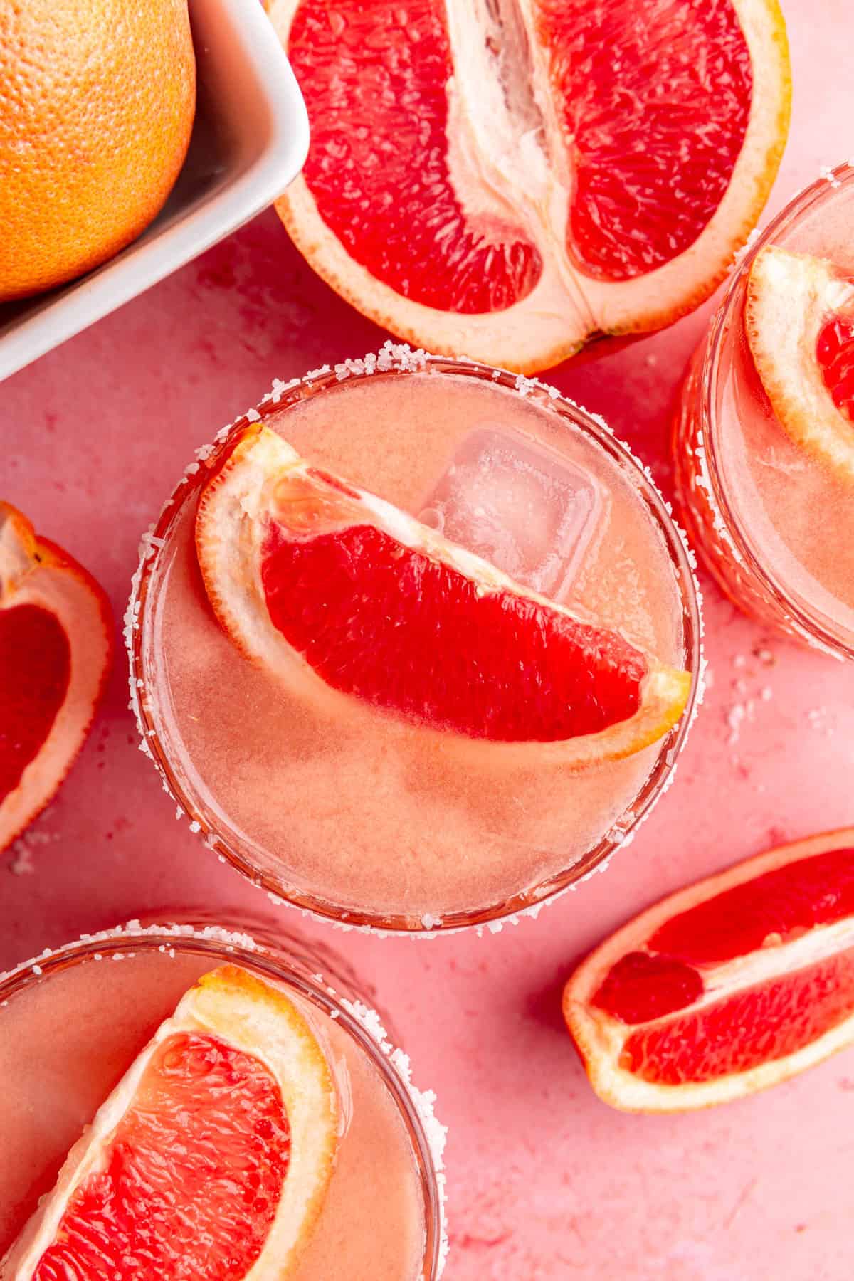 A top-down view of the grapefruit wedges in a few glasses of paloma mocktail.