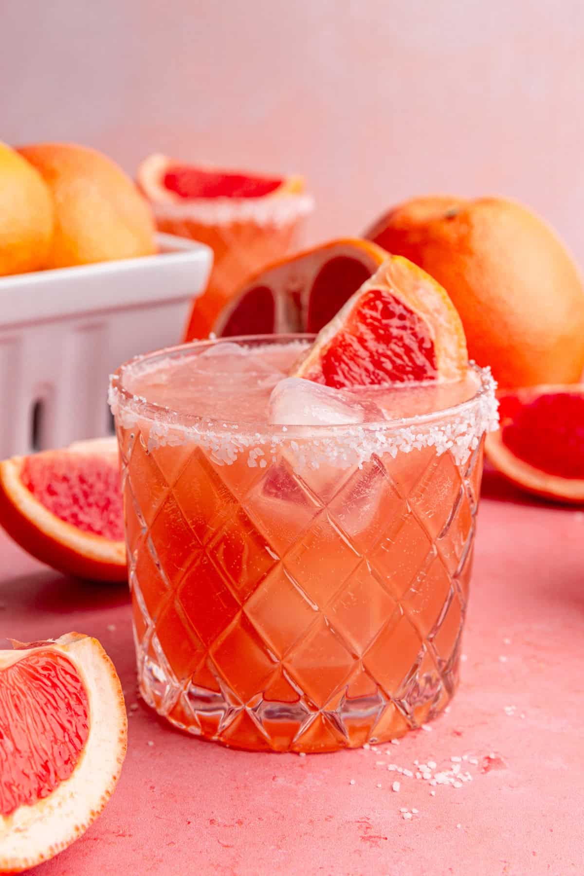 A glass of grapefruit mocktail, with a wedge of grapefruit in the glass.