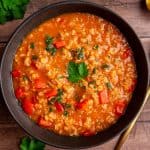 A bowl of Red Pepper Red Lentil Soup garnished with fresh parsley.