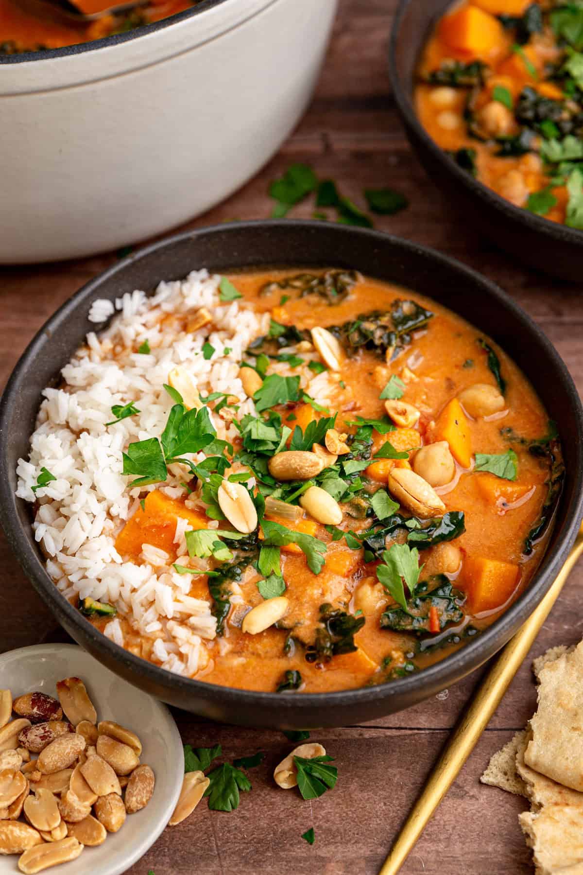 A bowl of Vegan African Peanut Stew, next to a pot of the stew.